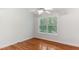 Bright bedroom featuring hardwood floors, white trim, and a large window at 5507 Vista View Ct, Raleigh, NC 27612