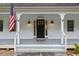 Close up of the front door and covered front porch with patriotic American flag at 5541 Old Still Rd, Wake Forest, NC 27587