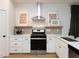 Kitchen area featuring stainless steel range, white cabinets, and modern fixtures with hardwood flooring at 612 E Ellerbee St, Durham, NC 27704