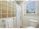 Bathroom featuring glass block wall, floral shower curtain, and window with blinds at 7112 Benhart Dr, Raleigh, NC 27613