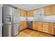Well-lit kitchen with stainless steel appliances, granite countertops, and wood cabinets and flooring at 7112 Benhart Dr, Raleigh, NC 27613