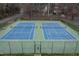 Aerial view of two fenced tennis courts with blue surface, surrounded by trees and greenery at 7112 Benhart Dr, Raleigh, NC 27613