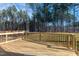 Wooden back deck with black metal railings overlooks a wooded backyard at 85 Purslane Dr, Franklinton, NC 27525