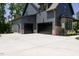 Three-car garage and side door entry to home, featuring black garage doors and concrete parking at 8620 Dukes Lake Rd, Zebulon, NC 27597