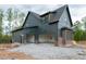 New construction showcasing a three-car garage with red brick trim and modern gray siding at 8620 Dukes Lake Rd, Zebulon, NC 27597