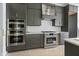 A modern kitchen features stainless steel appliances, gray cabinets, and white countertops at 8620 Dukes Lake Rd, Zebulon, NC 27597