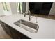 Close-up of a kitchen island featuring a stainless steel sink, sleek countertops, and gray cabinets at 8620 Dukes Lake Rd, Zebulon, NC 27597