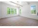 Bright living room featuring large windows, a decorative chandelier, and white trim at 8620 Dukes Lake Rd, Zebulon, NC 27597