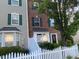 Charming two-story brick townhome showcasing a neat white picket fence and well-maintained landscaping at 8650 Neuse Landing Ln # 101, Raleigh, NC 27616