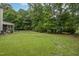 Large, grassy backyard with the house in the background, surrounded by lush, mature trees and greenery at 106 Teak Cir, Garner, NC 27529