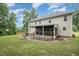 Backyard view of the home, showcasing the patio, stairs to the yard, a well-manicured lawn, and lush trees at 106 Teak Cir, Garner, NC 27529