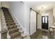 Elegant entryway featuring a staircase with patterned carpet and a sliding barn door at 1108 Agio Ct, Zebulon, NC 27597