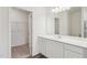 Bathroom vanity with white cabinets, sink, faucet, and large mirror with view of closet at 125 Gladstone Loop, Clayton, NC 27520