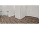 Hallway featuring wood-look flooring, white walls, and multiple doorways, creating a bright and open space at 133 Gladstone Loop, Clayton, NC 27520