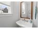 Clean powder room featuring a sleek sink, a vanity mirror, and natural light from a window at 1601 Bowery Dr, Raleigh, NC 27607