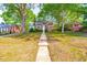 Charming front yard with mature trees, a long walkway, and established landscaping surrounding the home at 1617 Woodland Ave, Burlington, NC 27215