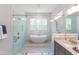 Bright bathroom featuring a freestanding tub, glass shower, white tile, granite countertop, and gray cabinets at 205 Riverine Dr, Pittsboro, NC 27312