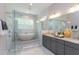 Bathroom featuring a freestanding tub, glass shower, gray cabinets, granite countertop, and a large vanity mirror at 205 Riverine Dr, Pittsboro, NC 27312