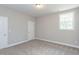 Well-lit bedroom showcases a neutral color scheme, a white door, carpet, and a window overlooking the outdoors at 205 Riverine Dr, Pittsboro, NC 27312