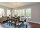 Bright dining room with a dark wood table, six chairs, chandelier, and a large window overlooking the wooded property at 205 Riverine Dr, Pittsboro, NC 27312