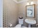 Powder room with patterned wallpaper and a gold framed mirror at 206 Arbor Dr, Elon, NC 27244