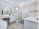 Bright bathroom featuring a tiled floor, double sinks, a walk-in shower, and a soaking tub at 206 Arbor Dr, Elon, NC 27244