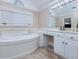 Large bathroom with a garden tub, white cabinets, and large mirror, filled with natural light at 206 Arbor Dr, Elon, NC 27244