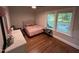 Bedroom with hardwood floors, large windows, and a cozy bed topped with a floral quilt and checkered pillows at 223 E Nash St, Spring Hope, NC 27882