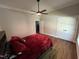 Bedroom with hardwood floors, ceiling fan, two closets, a large window, and a comfortable bed with red bedding at 223 E Nash St, Spring Hope, NC 27882