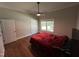 Bedroom with hardwood floors, a ceiling fan, two closets, a window, and a comfortable bed with red bedding at 223 E Nash St, Spring Hope, NC 27882