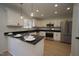 Well-lit kitchen featuring white cabinets, stainless steel appliances, dark granite countertops, and a breakfast bar at 3244 Marcony Way, Raleigh, NC 27610