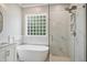Elegant bathroom features a soaking tub, a walk-in shower, and white marble-look tile at 3332 Cheswick Dr, Raleigh, NC 27609