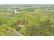 Aerial view of a house surrounded by woods and lush greenery with a nearby road and small lake at 3954 Piney Grove Church Rd, Siler City, NC 27344