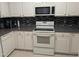 Well-appointed kitchen with white cabinets, dark countertops, and a complementary backsplash for a sleek design at 4502 Pale Moss Dr, Raleigh, NC 27606