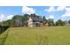 Spacious backyard highlighting lush green lawn and the back of the brick home with a screened-in porch at 80 Greta Ln, Henderson, NC 27537
