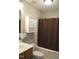 Functional bathroom featuring a toilet, tub with brown shower curtain, and cabinet above at 860 Bear Rd, Benson, NC 27504