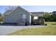 Rear view of home with covered back porch, outdoor fan, and access to a gravel parking area at 860 Bear Rd, Benson, NC 27504