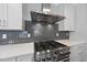 Close-up of the gas range, quartz countertop and gray subway tile backsplash in the modern kitchen at 10119 Second Star Ct, Raleigh, NC 27613