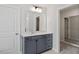 Bathroom with blue vanity cabinets, quartz countertop, mirror and glass enclosed shower at 104 Black Walnut Dr # 202, Garner, NC 27529