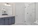 Bright bathroom with glass shower and large mirror above the blue cabinets at 104 Black Walnut Dr # 202, Garner, NC 27529