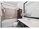 Well-lit bathroom boasts a shower-tub combo, modern vanity, dark wood cabinet and neutral tile at 1064 Blue Bird Ln, Wake Forest, NC 27587