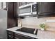 Close-up of a modern kitchen featuring granite countertops, a cooktop, stainless steel microwave, and stylish backsplash at 1064 Blue Bird Ln, Wake Forest, NC 27587