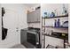 Well-equipped laundry room with gray washer, dryer, storage cabinets, and metal shelving unit for home supplies at 124 Alta Crest Ln, Garner, NC 27529