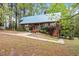 Charming home featuring a metal roof, lush landscaping, and a walkway through the trees to the back at 1355 Bowling Road, Fuquay Varina, NC 27526