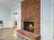 Living area features a warm brick fireplace and wood-look flooring at 1355 Bowling Road, Fuquay Varina, NC 27526