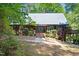 Charming wood home featuring a metal roof, lush landscaping, and a brick walkway to the front door at 1355 Bowling Road, Fuquay Varina, NC 27526
