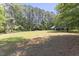 Expansive lot featuring a wooded perimeter and a home with light blue metal roof at 1355 Bowling Road, Fuquay Varina, NC 27526