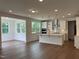 Open-concept kitchen boasts white cabinets, an island with a sink, stainless steel appliances, and wood floors at 159 Yellow River Way, Garner, NC 27529