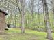 View of wooded lot with brick home and propane tank on a green lawn at 1622 N Carolina 98 Hwy W, Louisburg, NC 27549
