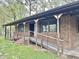 View of a charming brick home featuring a covered porch with wooden railings and a ramp at 1622 N Carolina 98 Hwy W, Louisburg, NC 27549